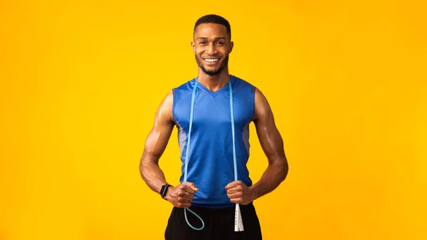 Knappe zwarte sportman met springtouw in oranje studio — Stockfoto