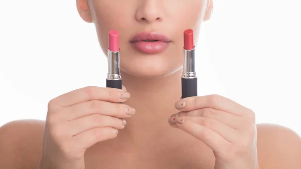 Difficult choice. Girl holding two lipsticks, white background — Stok fotoğraf