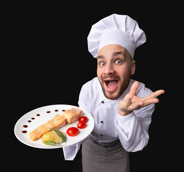 Chef divertido que ofrece el plato del salmón en la placa, tiro del estudio, ángulo alto — Foto de Stock