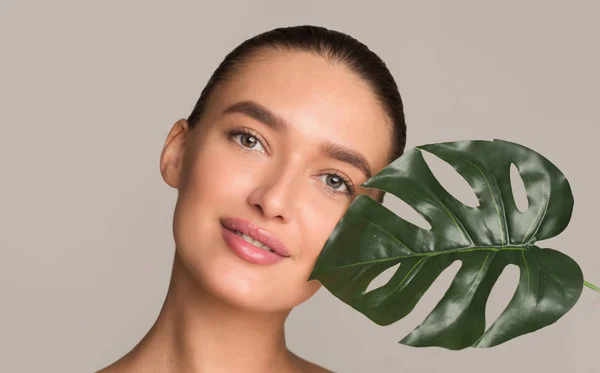 Concepto de belleza. Chica con hoja de palma verde cerca de la cara — Foto de Stock