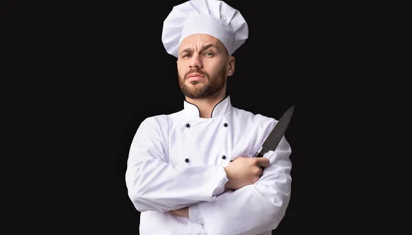 Poważny szef kuchni trzymając nóż patrząc na aparat pozowanie, Studio strzał — Zdjęcie stockowe