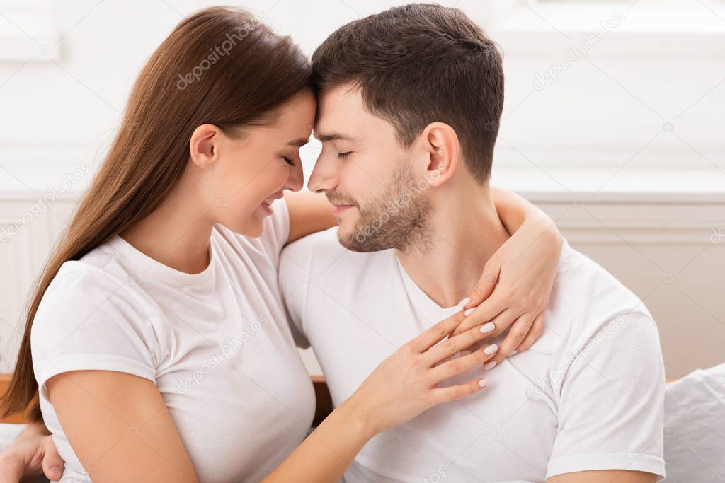 Couple Embracing Sitting In Bed In Bedroom In The Morning