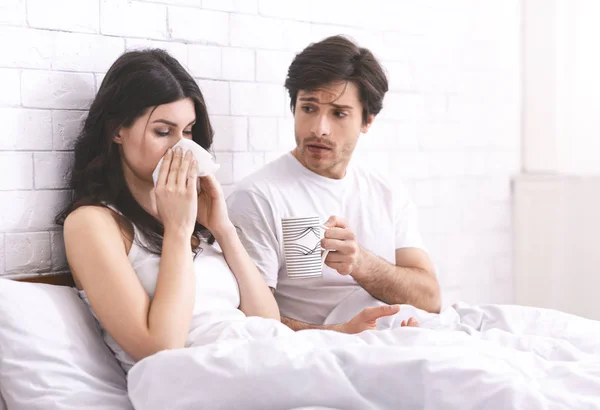 Cuidando marido dando vaso de agua a su esposa enferma en la cama —  Fotos de Stock