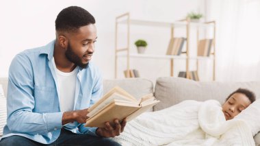 Bedtime story. Caring father reading book to sleeping daughter