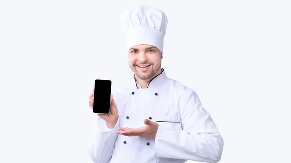 Restaurantchef zeigt Handy mit leerem Bildschirm auf weißem Hintergrund — Stockfoto