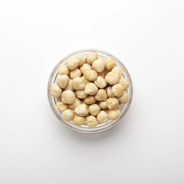 Pile of hazelnuts in glass bowl on white background — 스톡 사진