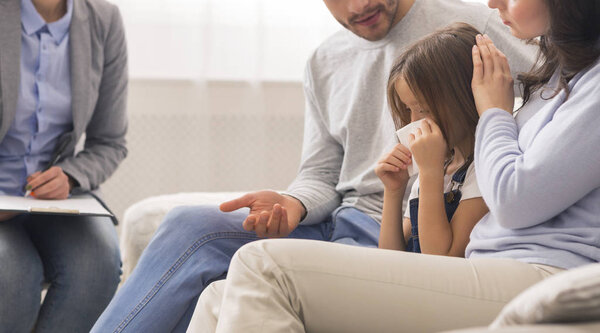 Маленькая девочка плачет в детском отделении психологов, заботясь о родителях утешая ее
