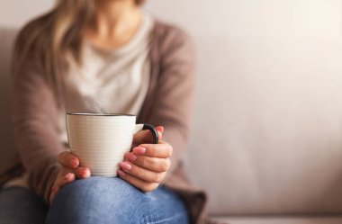 Cup of hot drink in hands of young woman