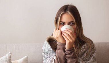 Young woman drinking hot coffee, empty space