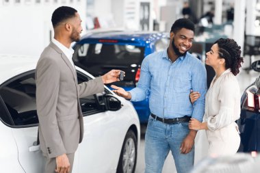 Family Buying Auto Taking Key From Car Dealer In Store