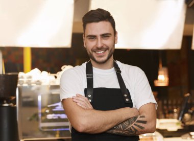 Smiling Barkeeper Guy Standing Near Counter With Coffee-Machine In Coffee-Shop