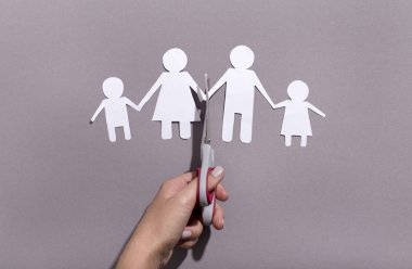 Female hand cutting Paper family chain on gray background