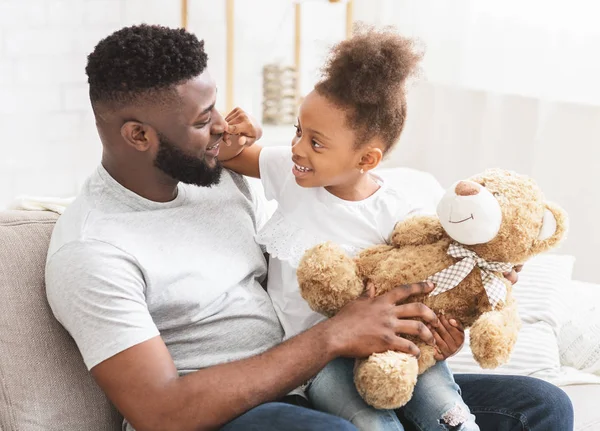 Afro pequeña hija acurrucándose con su papá mientras juegan juntos —  Fotos de Stock