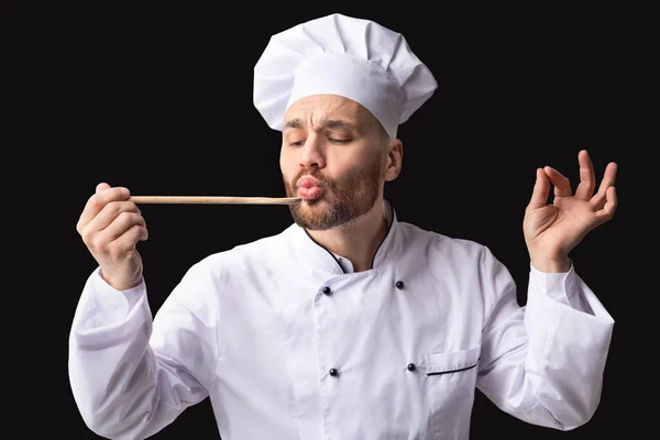 Gurmánský kuchař ochutnávka pokrmů Schvalování chutě přes černé pozadí — Stock fotografie
