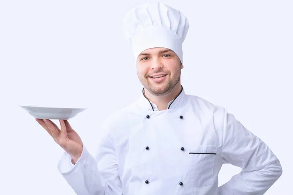 Шеф-повар держит пустую тарелку позируя в студии на белом фоне — стоковое фото