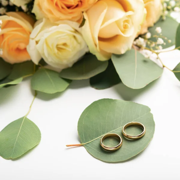 Deux anneaux dorés sur feuille verte, bouquet nuptial — Photo