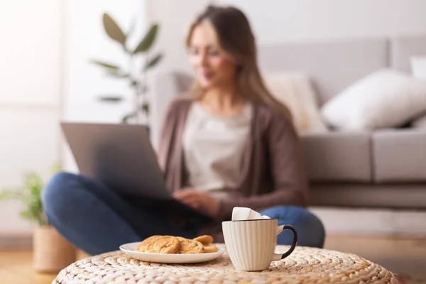 Woman browsing on laptop at home, focus on coffee cup — 图库照片