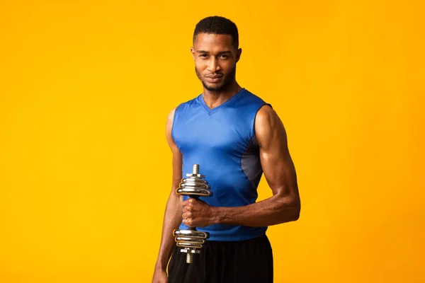 Afro bodybuilder pumping up biceps with dumbbells — Stok fotoğraf