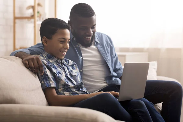 Alegre afro chico y su padre usando ordenador portátil en casa — Foto de Stock