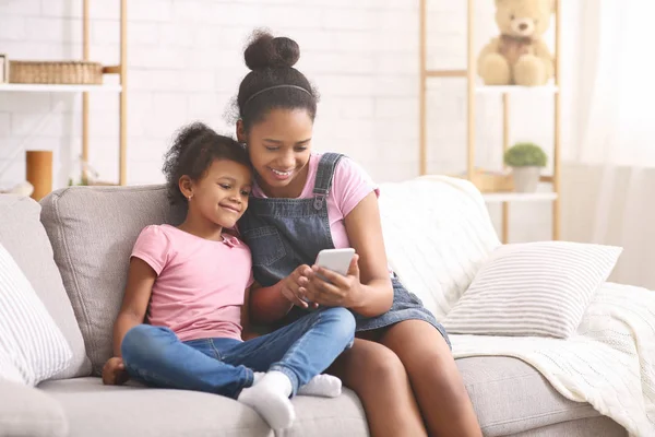 Afro-Amerikaanse meisjes browsen op mobiele telefoon thuis — Stockfoto