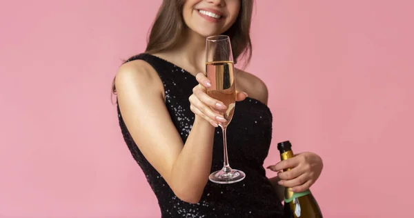 Fille méconnaissable offrant verre de champagne à la caméra, posant sur fond rose — Photo