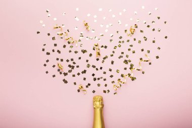 Bottle of champagne and confetti on pink background