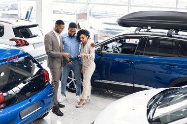 Couple Buying New Car Choosing Auto With Manager In Dealership