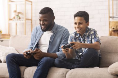 Excited Black Boy Playing Video Games With Dad At Home