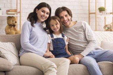 Portrait of cute little girl posing at home with her parents