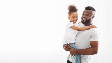 Handsome black father holding his little girl over white