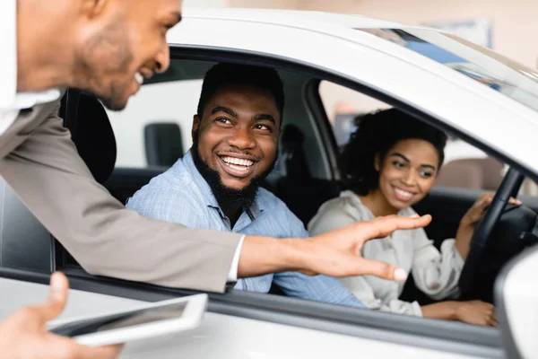 Щаслива пара купує автомобіль розмовляє з продавцем сидячи в авто — стокове фото
