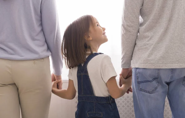 Милая маленькая девочка держит за руки своих неузнаваемых родителей — стоковое фото