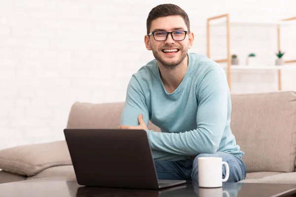 Bem sucedido Freelancer Guy no computador portátil sentado no sofá interior — Fotografia de Stock