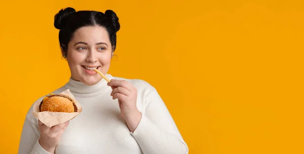 Bruneta baculatá dívka jíst hamburger a hranolky, těší rychlé občerstvení — Stock fotografie
