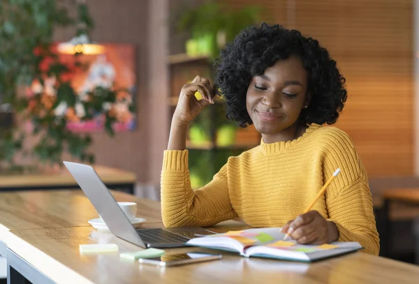 Chica negra soñadora anotando pensamientos, pasando tiempo en la cafetería — Foto de Stock