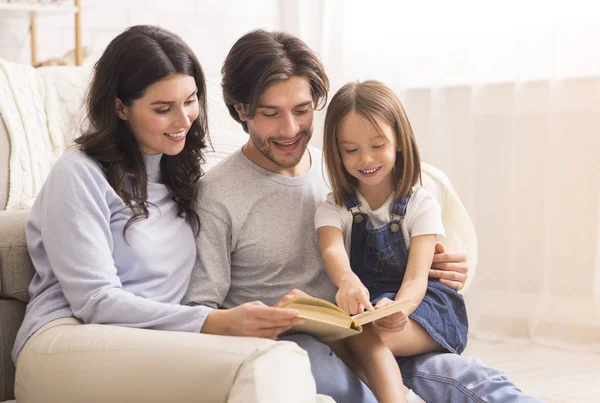 Parents teaching their little daughter how to read at home — 图库照片