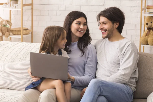 Adorable little girl using laptop with her parents at home — 스톡 사진