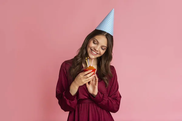 Young Girl In Birthday Hat Looking At Cupcake With Lighting Candles — Stok fotoğraf