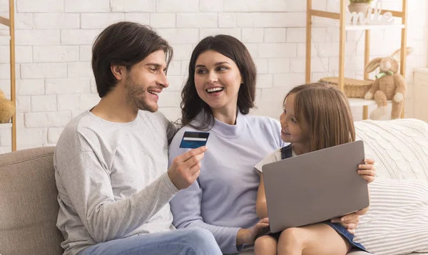 Felice famiglia di tre fare shopping online con il computer portatile a casa — Foto Stock
