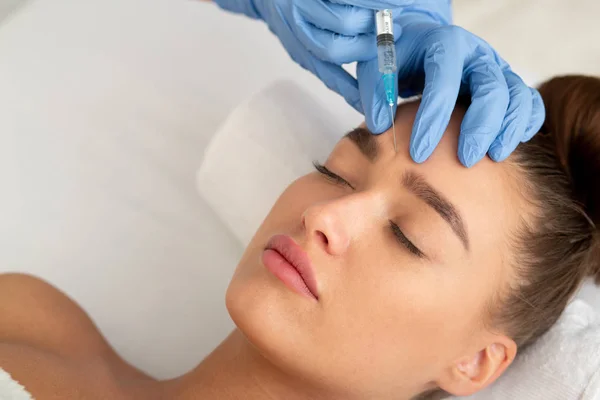 Beauty procedures. Woman receiving injection in forehead — Stockfoto