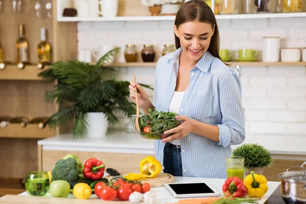 Young woman mixing healthy salad and using tablet — 스톡 사진