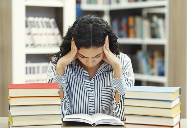 Stresszes latin lány készül vizsgára a könyvtárban — Stock Fotó