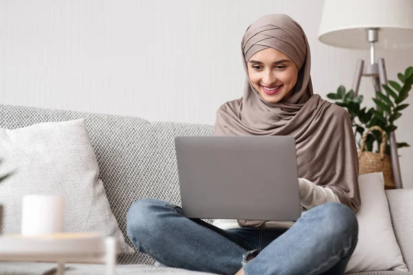 Jeune fille musulmane réservation hôtel en ligne, en utilisant un ordinateur portable à la maison — Photo