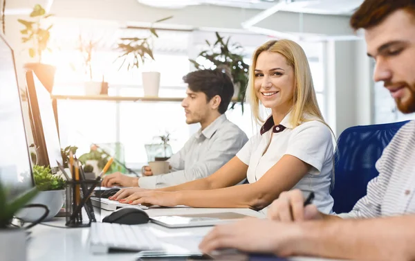 Cheerful blonde girl working in office, sitting next to colleagues — Stockfoto