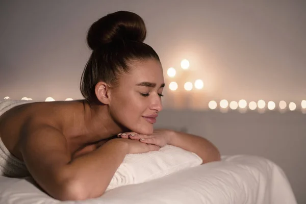 Koncepcja masażu. Zrelaksowana kobieta w spa, leżąca na stole do masażu — Zdjęcie stockowe