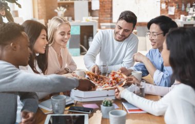 Happy colleagues eating pizza together in office