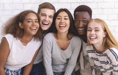 Portrait of happy multiethnic young friends over white wall background