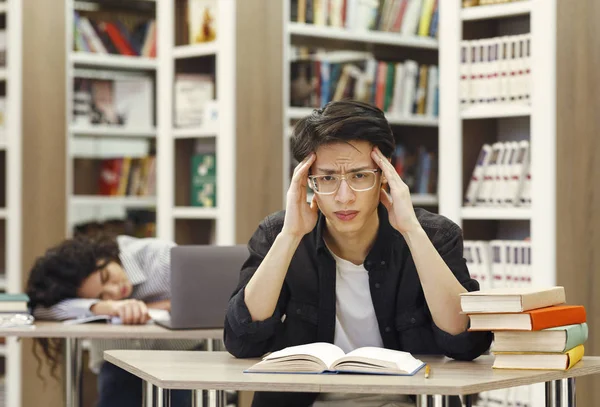 Zmęczeni studenci studiujący w bibliotece uniwersyteckiej — Zdjęcie stockowe