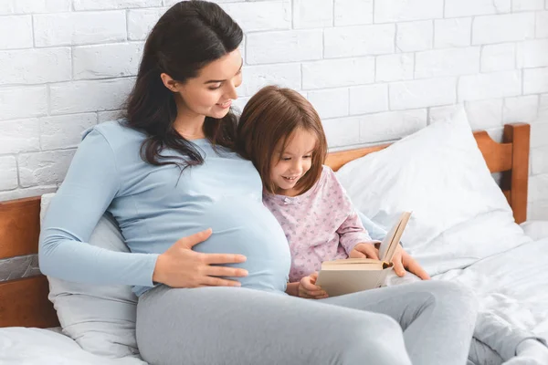 Embarazada dama leyendo cuentos de hadas a su pequeña linda hija — Foto de Stock