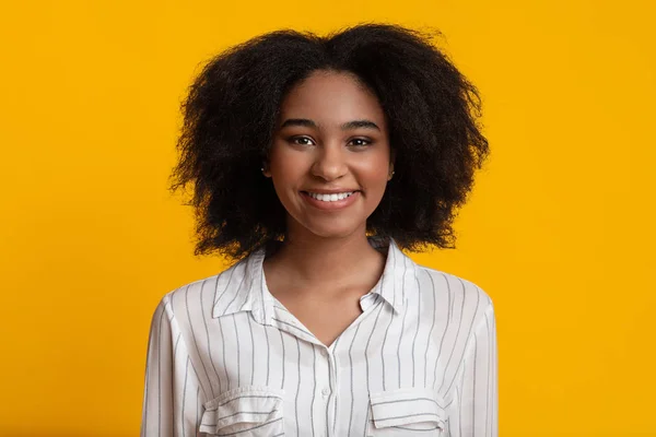 Positivo afro chica sonriendo en cámara posando sobre amarillo estudio fondo —  Fotos de Stock